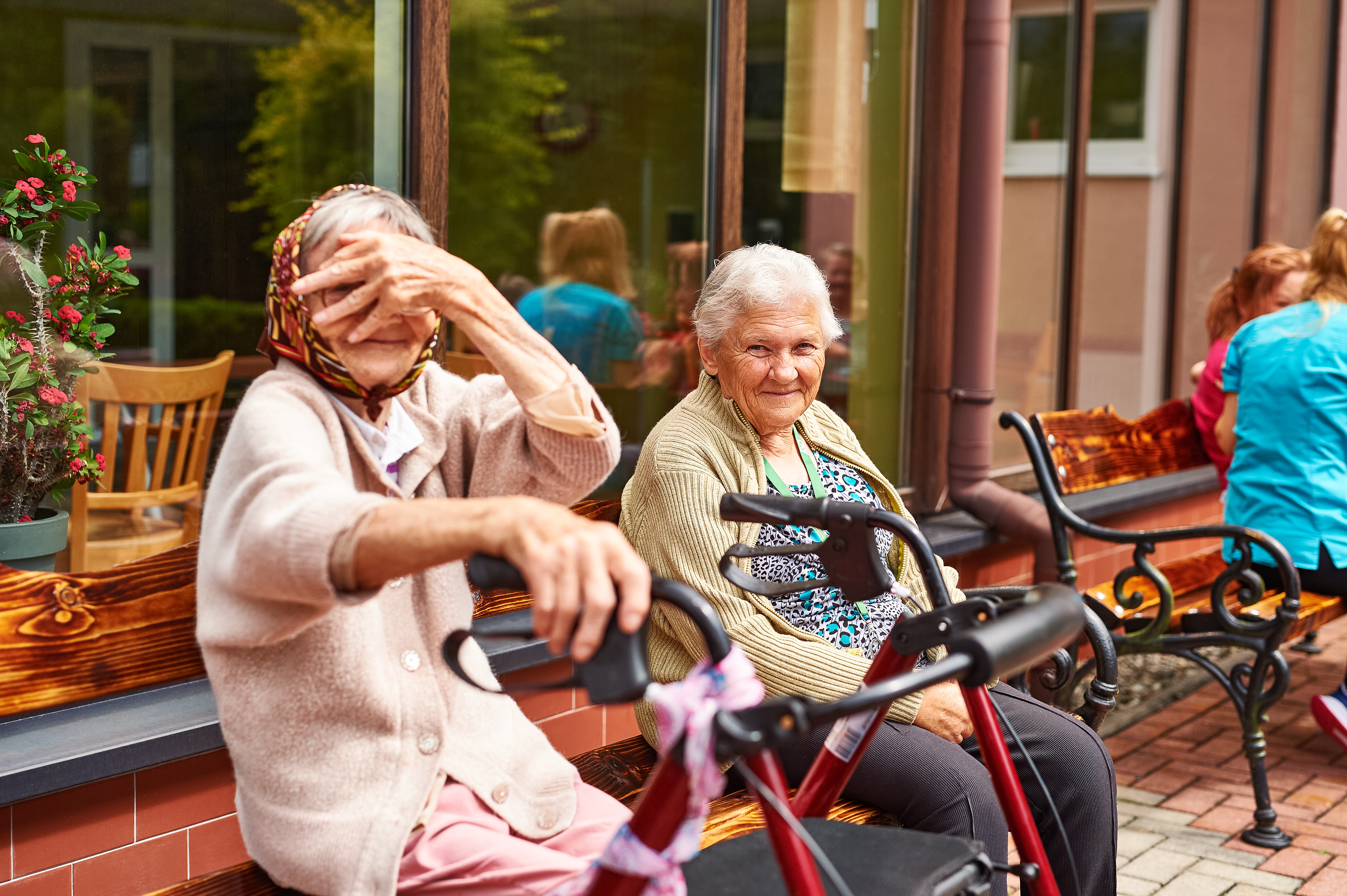 Dwie Panie z domu opieki, jedna z nich zasłania swoją twarz lewą ręką