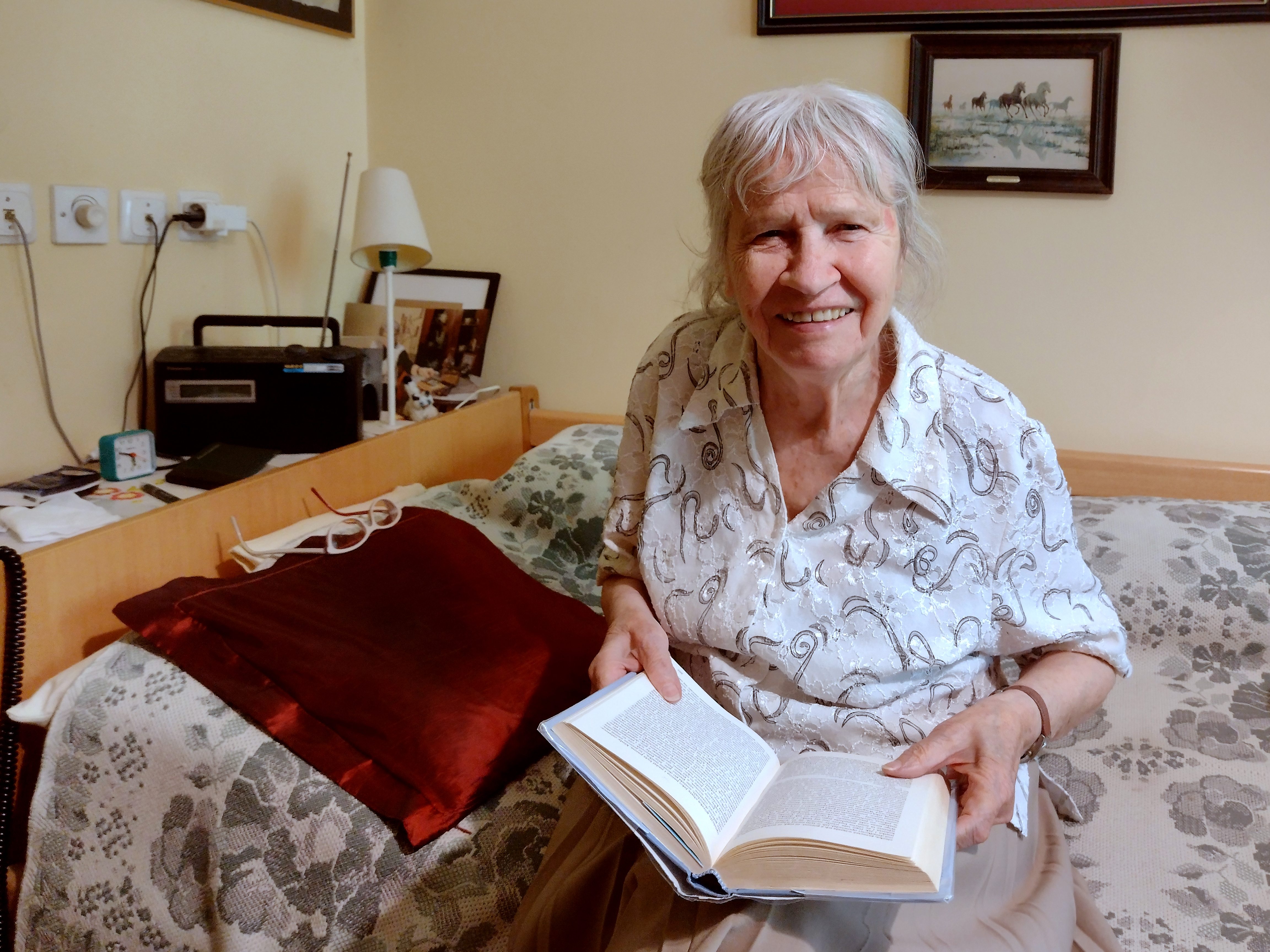 Pani siedząca na łóżku i czytająca książkę