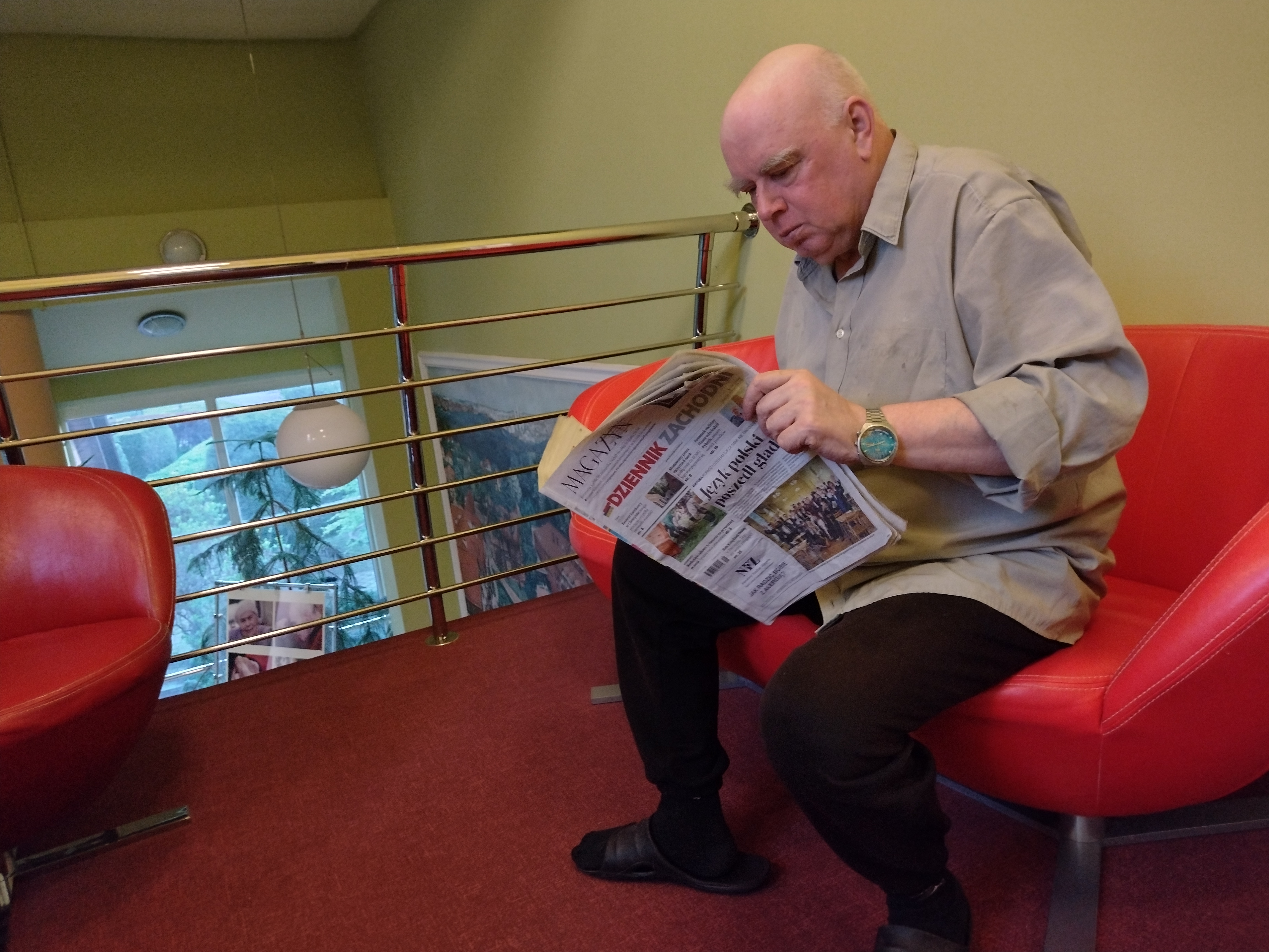 Mieszkaniec czytający gazetę na czerwonym fotelu
