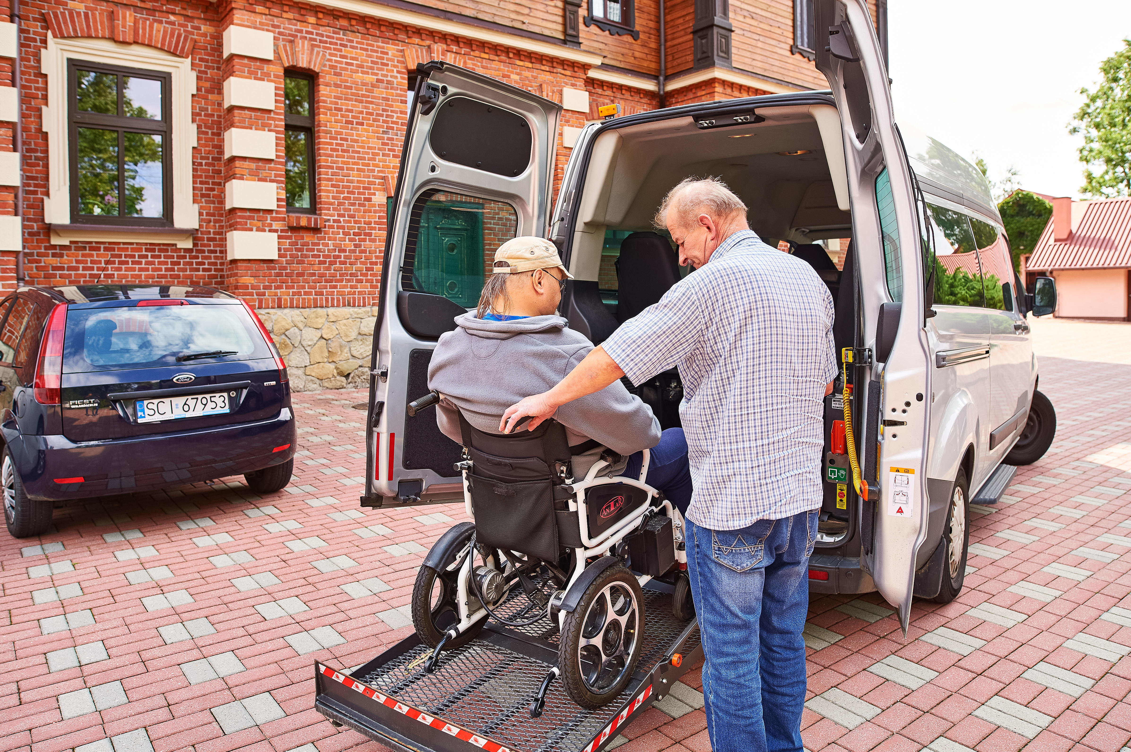 Mieszkaniec wsiadający do samochodu za pomocą specjalnego podjazdu dla osób niepełnosprawnych