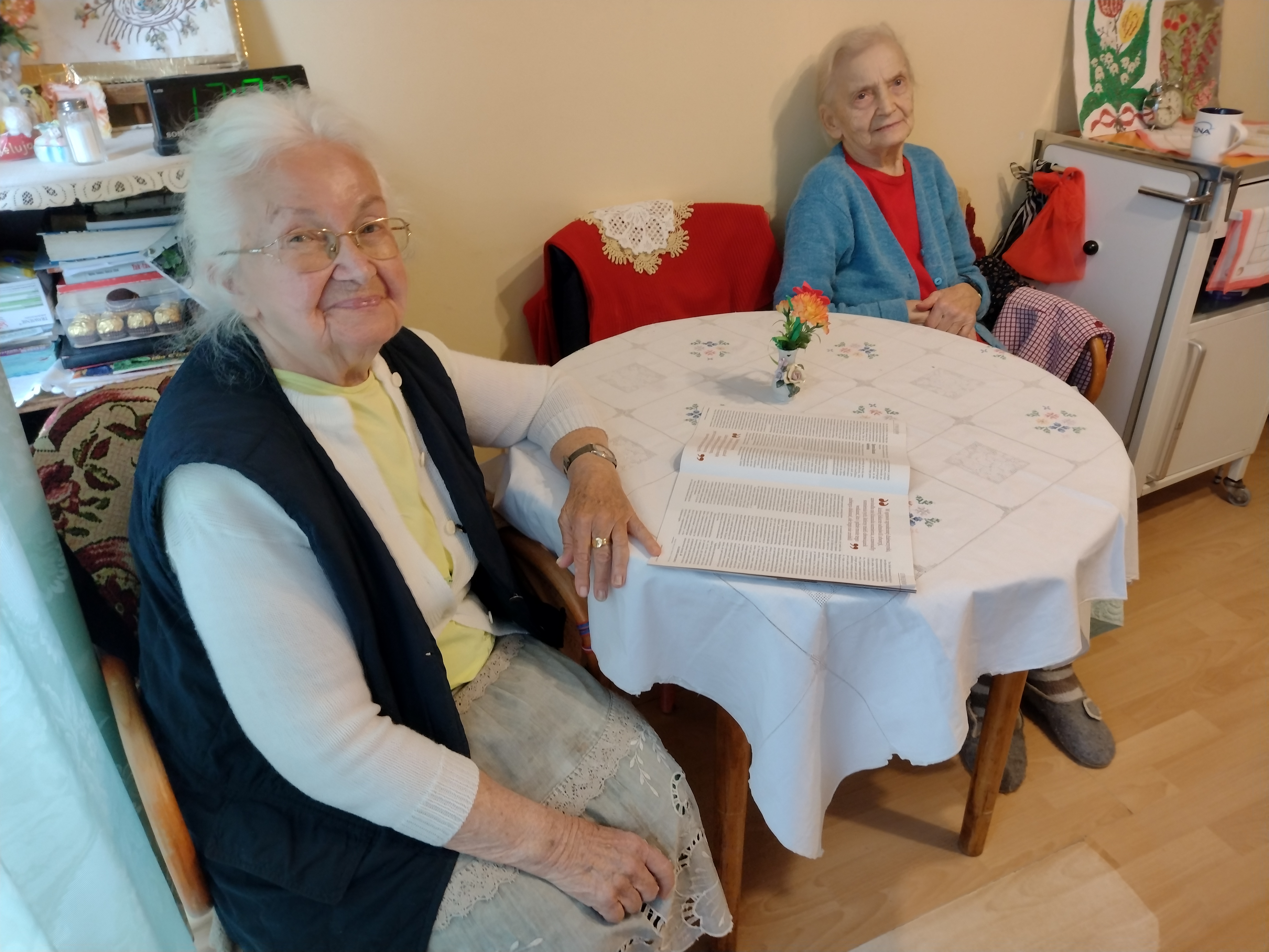 Panie przy stole, jedna czyta gazetę