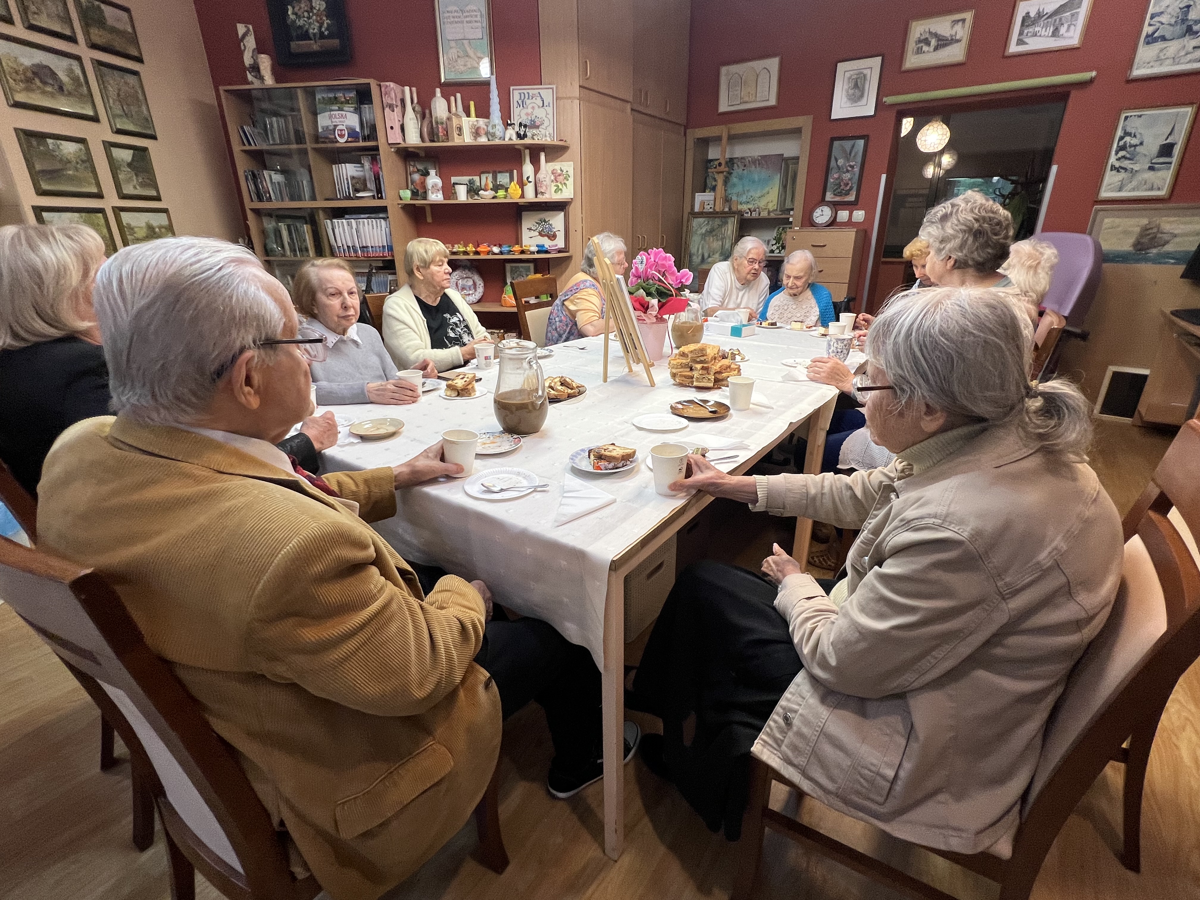 Grupa seniorów wokół stołu przy okolicznościowym torcie