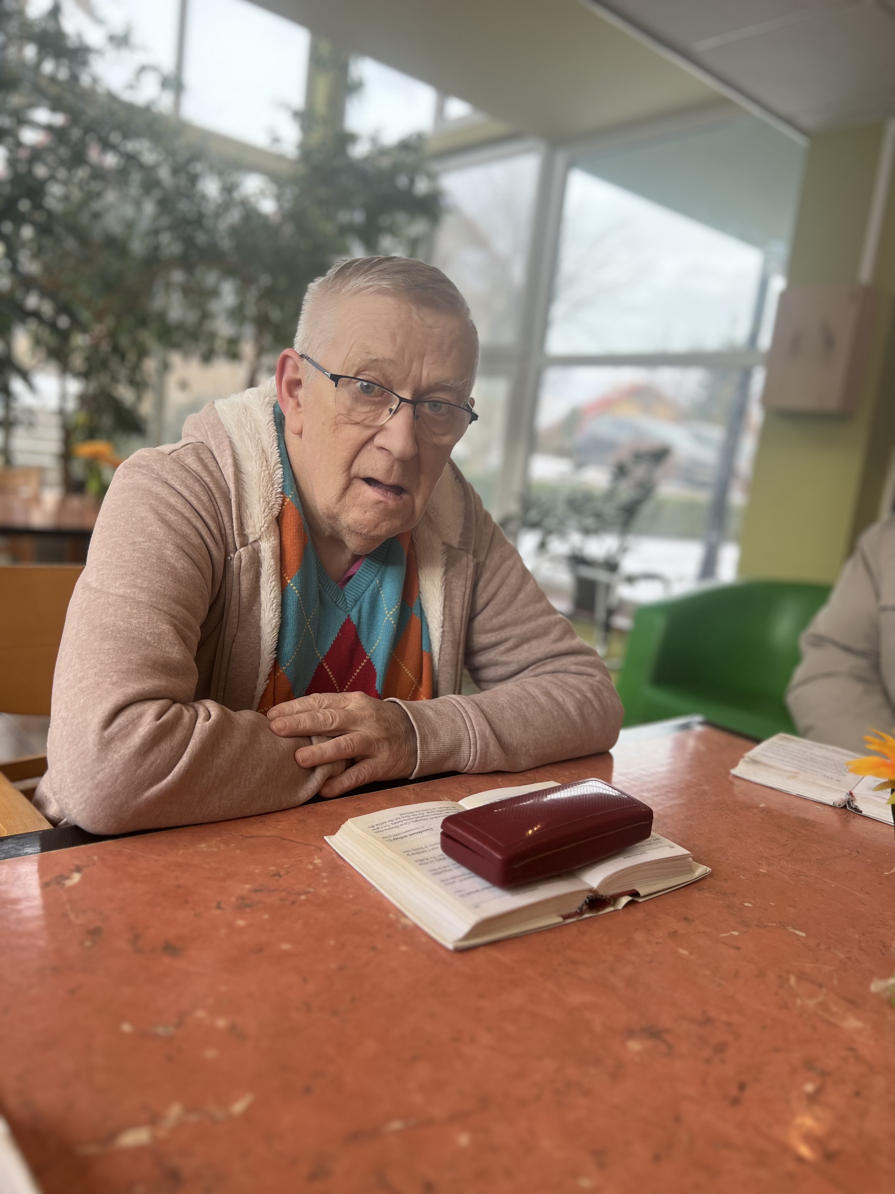 Senior w okularach pochylony nad śpiewnikiem