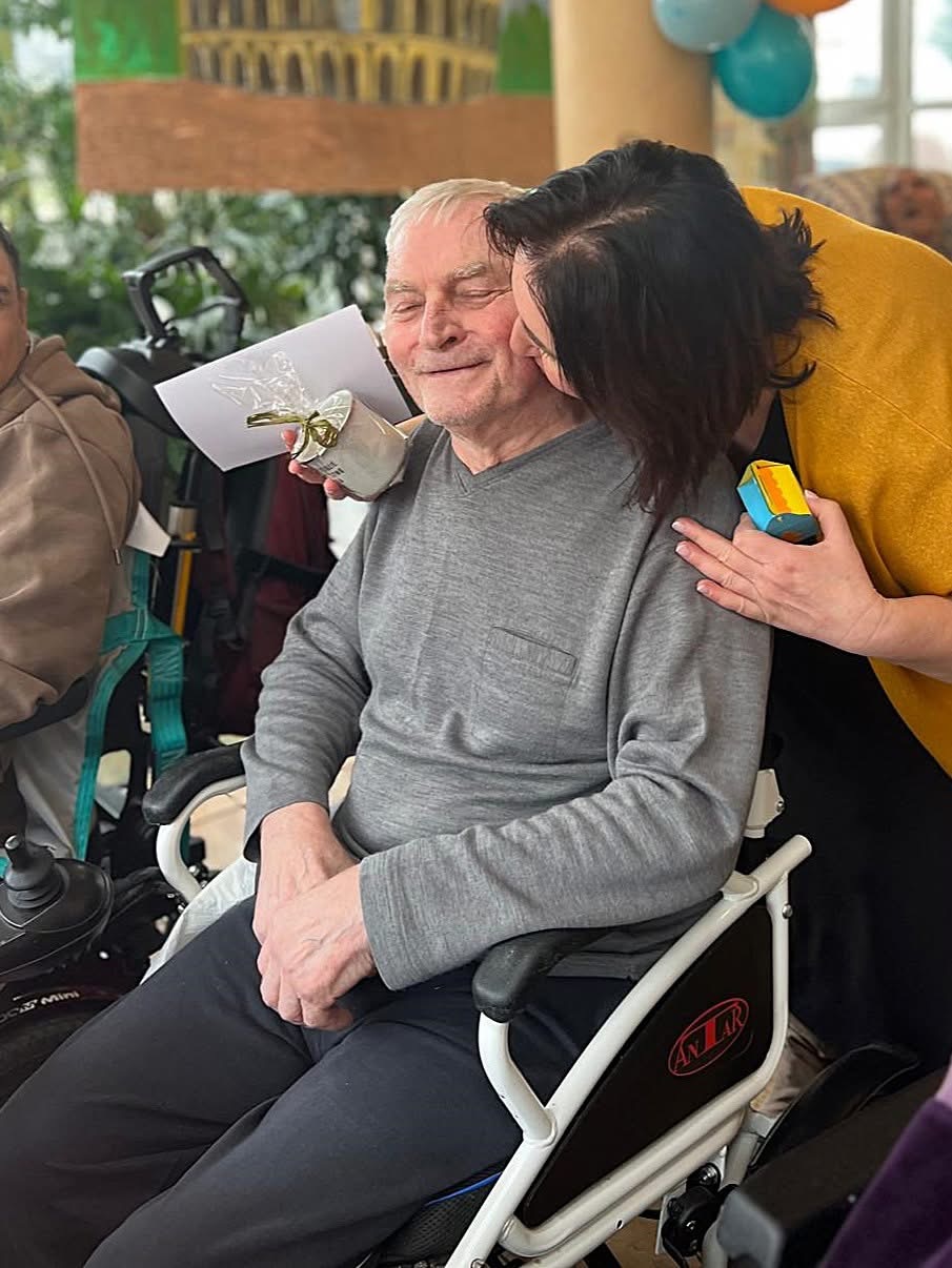 Zadowolony senior tulony przez kobietę, która składa życzenia